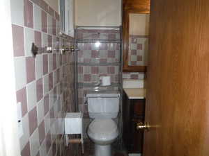 Master Bathroom with tasteful backsplash, toilet, and tile walls