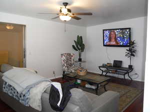 Living room with ceiling fan and dark hardwood / wood-style flooring