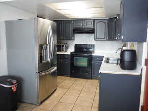 Kitchen with appliances with stainless steel finishes, light tile patterned floors, and sink