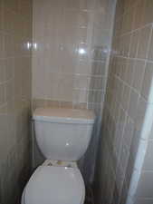 Bathroom featuring toilet and tile walls