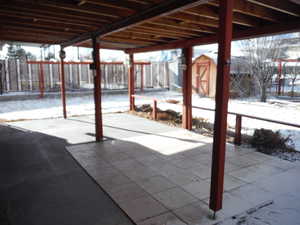 Snow covered patio featuring a storage shed