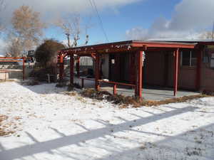 Snow covered back of property featuring a patio