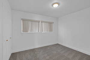 Unfurnished room featuring carpet flooring, a textured ceiling, and brick wall