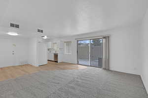 Unfurnished living room featuring light hardwood / wood-style flooring, a textured ceiling, and sink