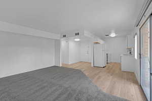 Basement featuring white refrigerator, light hardwood / wood-style flooring, and sink