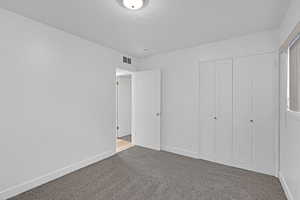 Unfurnished bedroom with carpet flooring, a textured ceiling, and a closet