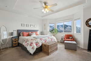 Master bedroom featuring a mountain view, ceiling fan, and a tray ceiling