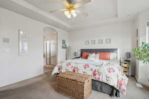 Master Bedroom with walk in closet, a raised ceiling, and ceiling fan.