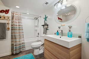 Full bathroom with shower / bath combo, tasteful backsplash, tile style hardwood  floors, toilet, and vanity