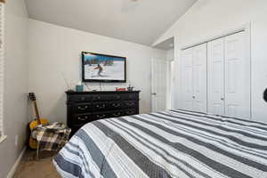 Carpeted bedroom featuring a closet and lofted ceiling