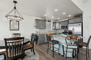 Kitchen featuring gray cabinetry, a center island, decorative backsplash, appliances with stainless steel finishes, and dark hardwood / wood-style LVP flooring