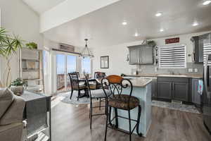 Kitchen with decorative light fixtures, gray cabinets, dark hardwood / wood-style LVP flooring, and dishwasher