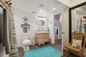 Bathroom featuring tile wood-type flooring, vanity, and toilet