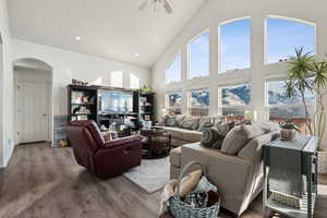 Living room with ceiling fan, plenty of natural light, high vaulted ceiling, and wood-type LVP flooring