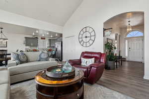 Living room featuring plenty of natural light, high vaulted ceiling, dark hardwood / wood-style LVP floors, and a notable chandelier