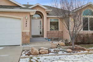 Snow covered property entrance featuring a garage