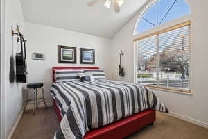 Carpeted bedroom #2 featuring ceiling fan and lofted ceiling.