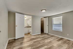 Unfurnished bedroom with ensuite bathroom, light wood-type flooring, and sink