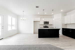 Kitchen with backsplash, visible vents, appliances with stainless steel finishes, and a chandelier