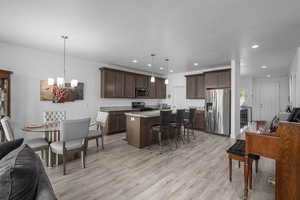 Kitchen featuring a breakfast bar, a center island with sink, decorative light fixtures, and appliances with stainless steel finishes