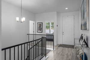 Foyer entrance with an inviting chandelier and light hardwood / wood-style flooring