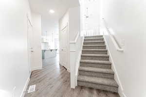 Stairway featuring visible vents, ceiling fan, wood finished floors, and baseboards