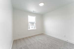 Spare room featuring baseboards, visible vents, a textured ceiling, and carpet