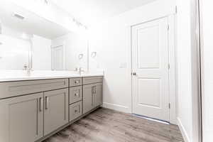Full bathroom featuring wood finished floors, double vanity, a sink, baseboards, and visible vents