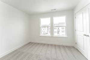 Unfurnished bedroom featuring baseboards, visible vents, and carpet floors