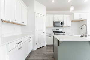 Kitchen with recessed lighting, a sink, stainless steel appliances, dark wood-type flooring, and white cabinets