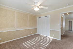 Unfurnished bedroom with carpet, ceiling fan, ornamental molding, and a closet