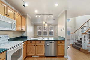 Kitchen featuring white appliances, sink, ceiling fan, ornamental molding, and light hardwood / wood-style floors