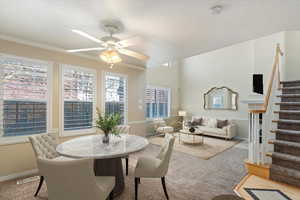 Carpeted dining space with a wealth of natural light, ceiling fan, and ornamental molding