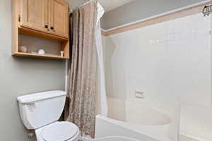 Bathroom with shower / bath combination with curtain and toilet