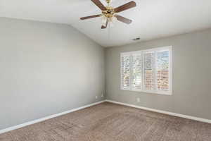 Carpeted empty room with ceiling fan and lofted ceiling