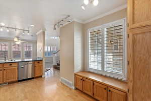 Kitchen featuring light wood-type flooring, ceiling fan, crown molding, sink, and dishwasher