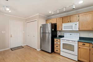 Kitchen with light brown cabinets, white appliances, track lighting, light hardwood / wood-style flooring, and ornamental molding