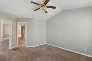 Carpeted spare room featuring ceiling fan and vaulted ceiling