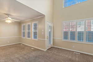 Spare room featuring ceiling fan, plenty of natural light, ornamental molding, and carpet floors