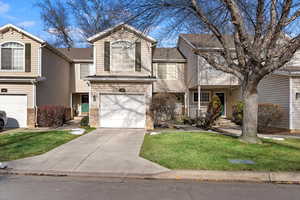 View of front of property with a garage and a front lawn