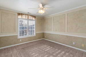 Empty room with carpet, ceiling fan, and crown molding