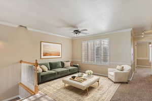 Carpeted living room featuring ceiling fan, a textured ceiling, and ornamental molding