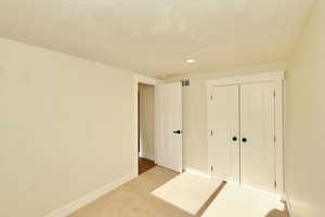 Unfurnished bedroom with a closet, carpet, and a textured ceiling