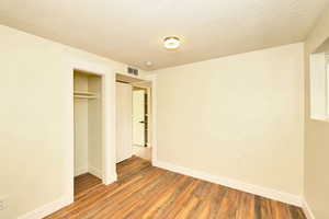 Unfurnished bedroom with hardwood / wood-style flooring, a textured ceiling, and a closet