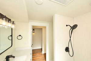 Bathroom featuring a shower, sink, a textured ceiling, and hardwood / wood-style flooring