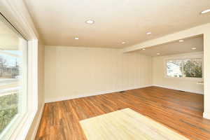 Empty room featuring hardwood / wood-style floors, a textured ceiling, and beam ceiling