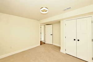 Unfurnished bedroom with light colored carpet, a textured ceiling, and a closet