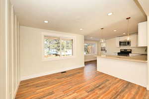 Kitchen with white cabinets, pendant lighting, stainless steel appliances, and light hardwood / wood-style flooring