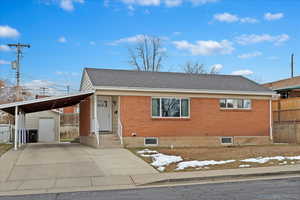 View of front of home with a shed and a carport