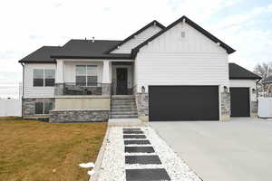 View of front of home with a front yard, a garage, and covered porch